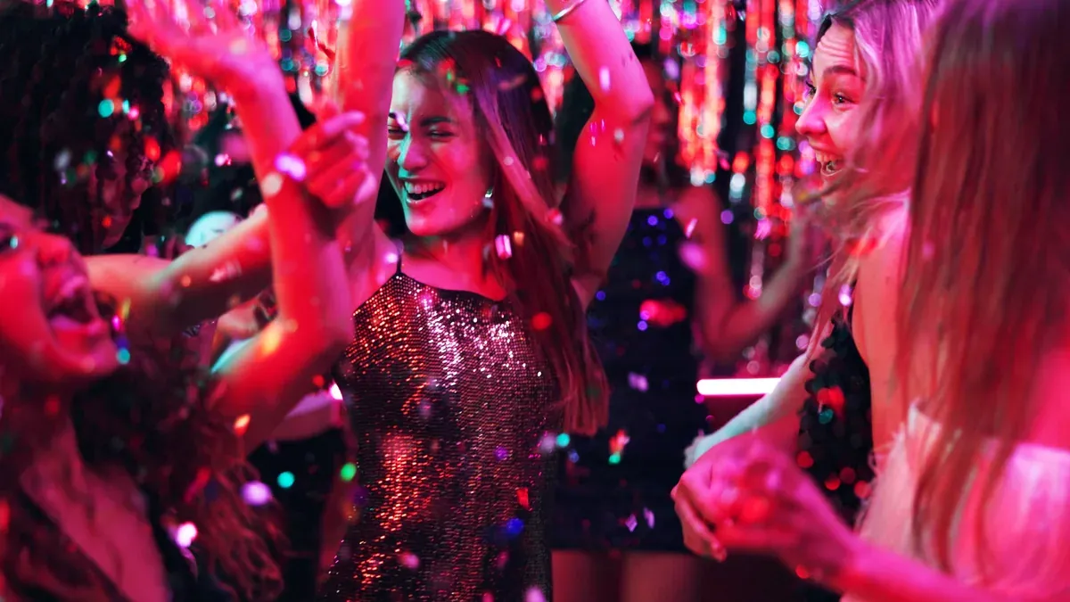 Gjester som danser på dansegulvet i en musikklubb mens konfetti faller
