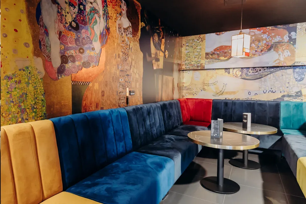 Fargerike polstrede restaurantsofaer i VIP-sonen på Klub Hype mot veggmalerier